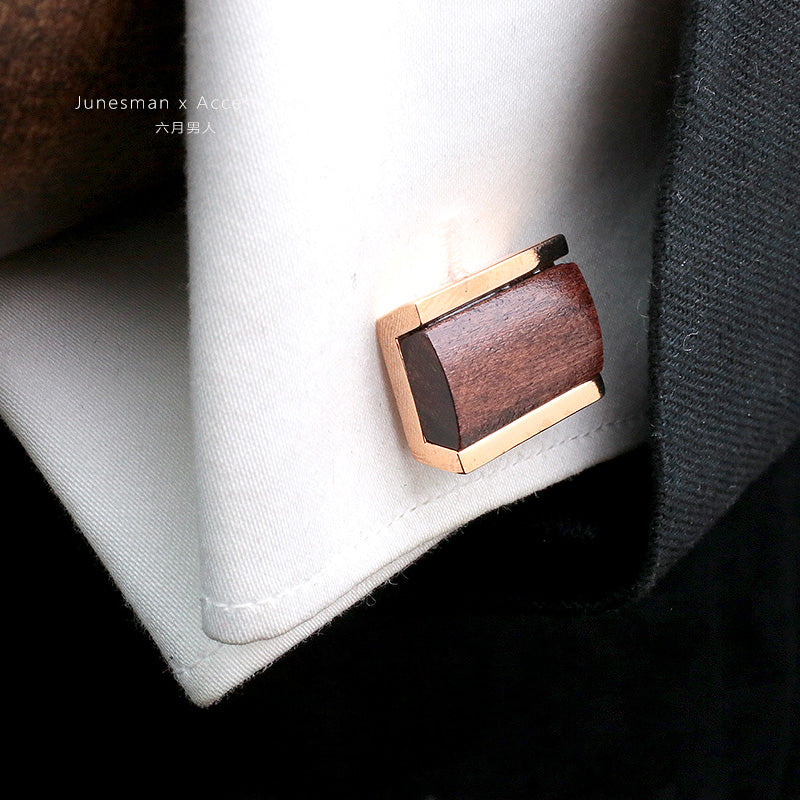 A pair of customized French shirt cufflinks with a wooden centerpiece and gold - toned metal edges, placed on a white shirt cuff. These hand - crafted cufflinks are a unique and personalized wooden wedding gift option.