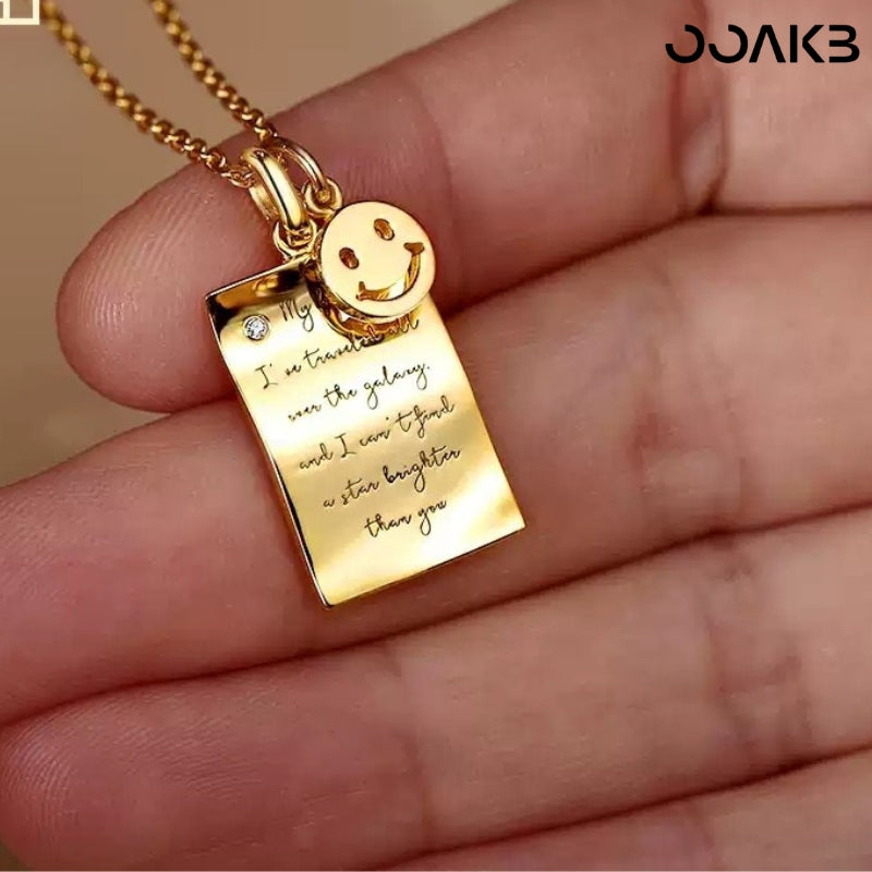 Gold love note necklace with engraved message and smiley charm, ideal 1st anniversary gift.