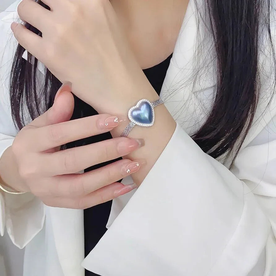 Blue Iridescent Pearl Heart Halo Bracelet — wrist-worn view over a white blazer sleeve