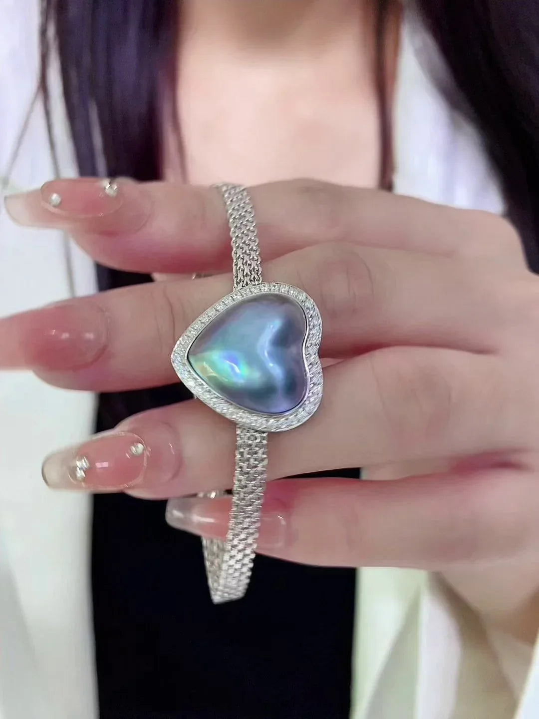 Blue Iridescent Pearl Heart Halo Bracelet — hand-held close-up showing the heart scale