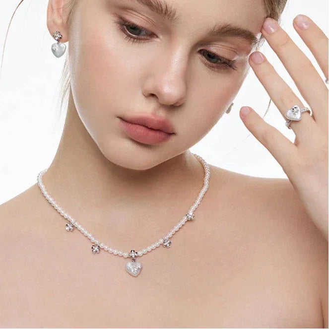 Pearl Heart Necklace with Floral Stations — model portrait coordinating the necklace with a ring