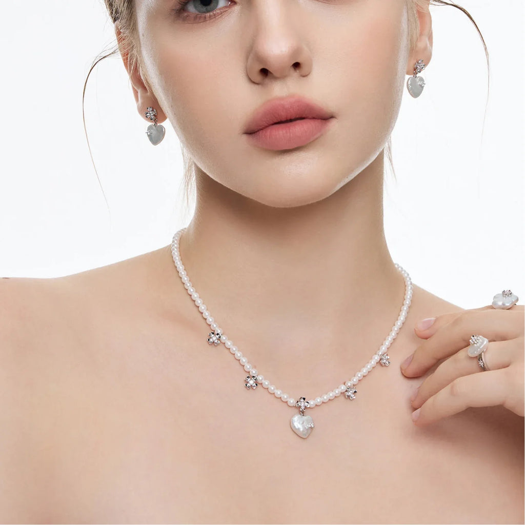 Pearl Heart Necklace with Floral Stations — front model portrait wearing the necklace with matching earrings