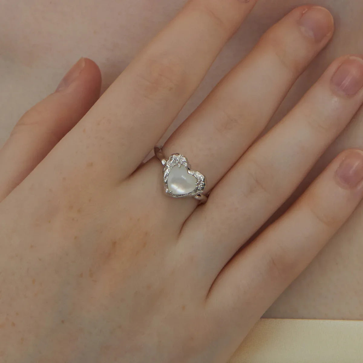 Open Pearl Heart Ring — hand-worn close-up showing the heart scale