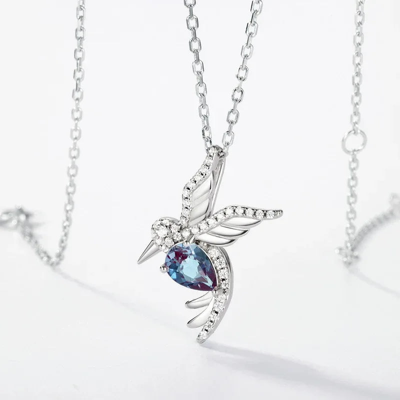 Bird-shaped pendant necklace with a Alexandrite body, product laid flat on a white background
