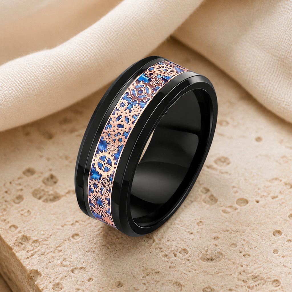 Black ceramic tungsten ring with a blue and rose-gold-tone gear-pattern inlay on beige stone