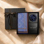 Open black gift box with a blue patterned cotton handkerchief, wax seal and silver accessory