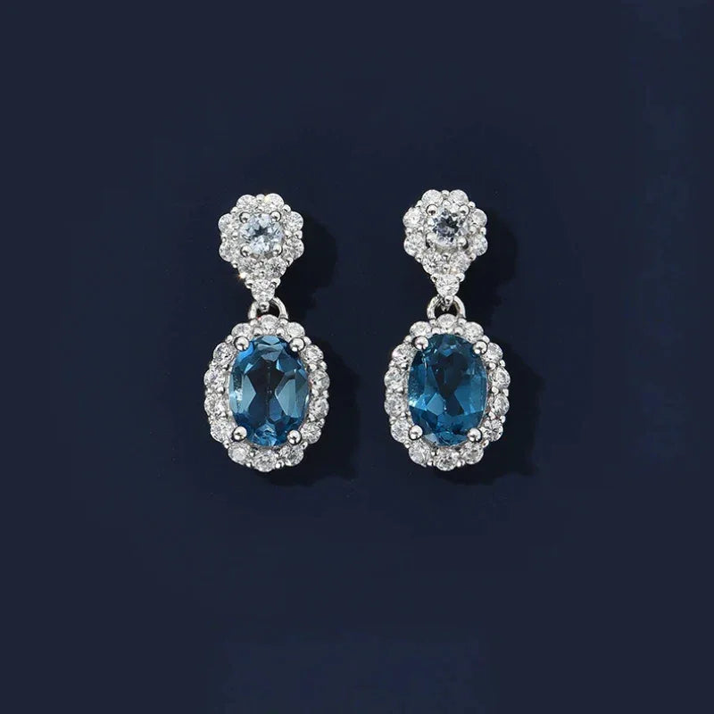 Blue Topaz Oval Halo Drop Earrings worn on the hand
