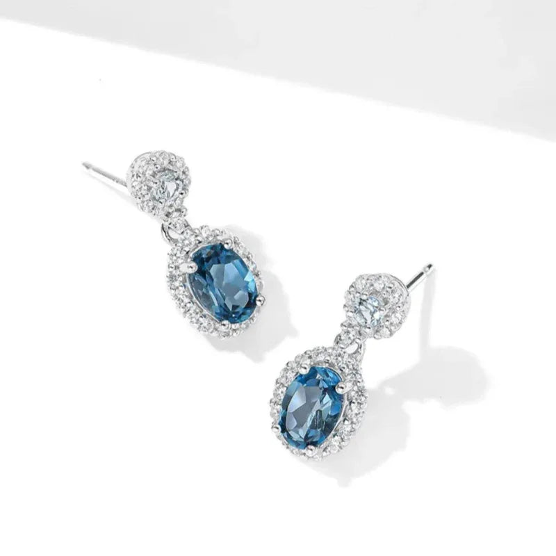 Blue Topaz Oval Halo Drop Earrings worn on the hand from another angle