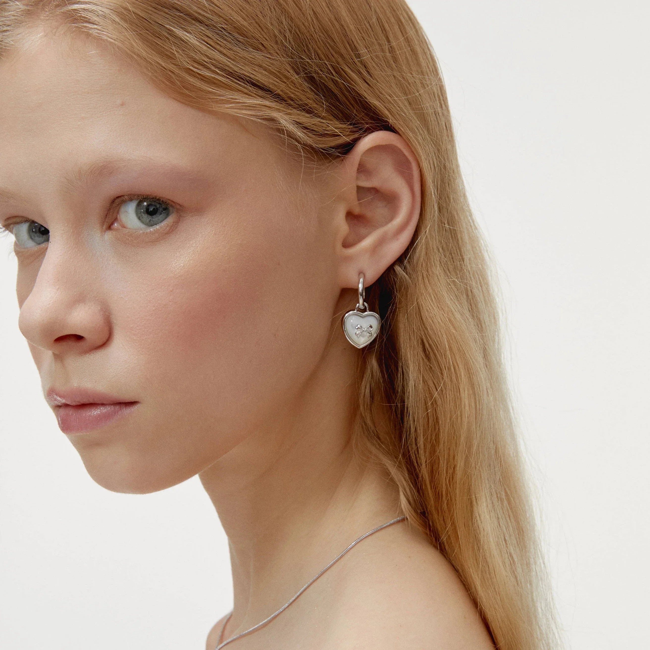 Pearl Heart Drop Earrings with Bow Detail — left-ear worn portrait