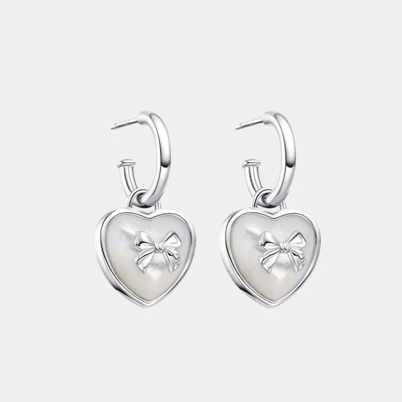 Pearl Heart Drop Earrings with Bow Detail — front pair of silver-tone hoops with heart drops and raised bow motifs