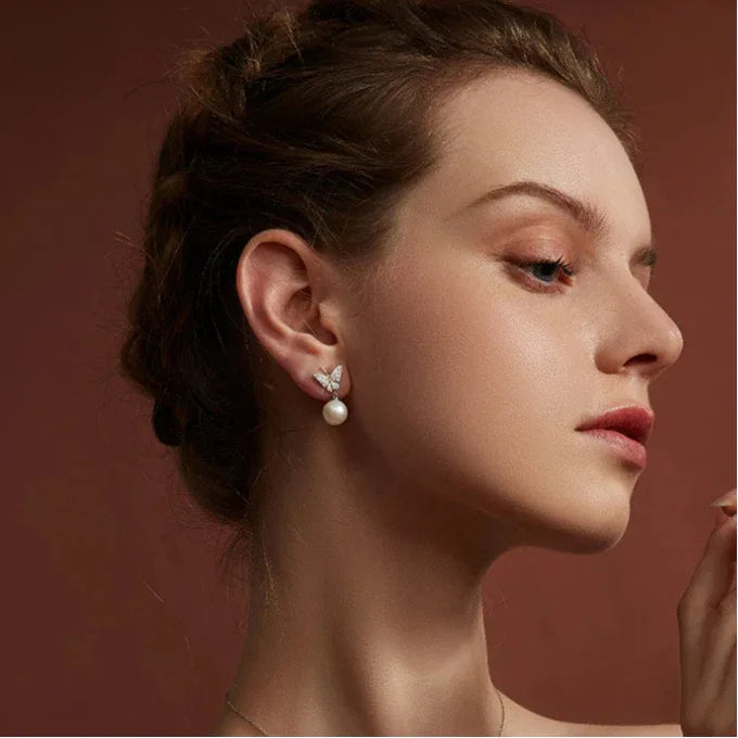 Butterfly Pearl Drop Earrings in Platinum-Plated S925 Silver — right-facing model portrait showing the earring profile
