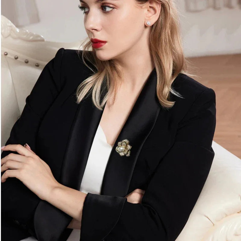 Shell Pearl Camellia Brooch — seated model wearing the brooch on a dark blazer