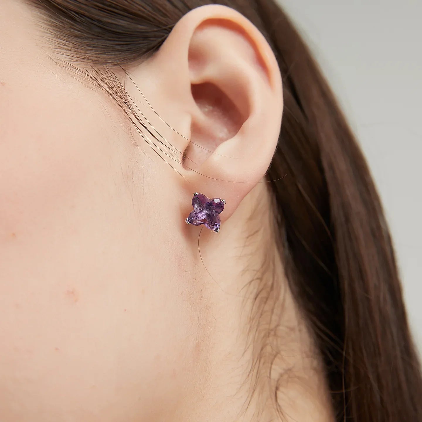 clover-cut amethyst stud earrings worn on the ear from a second angle