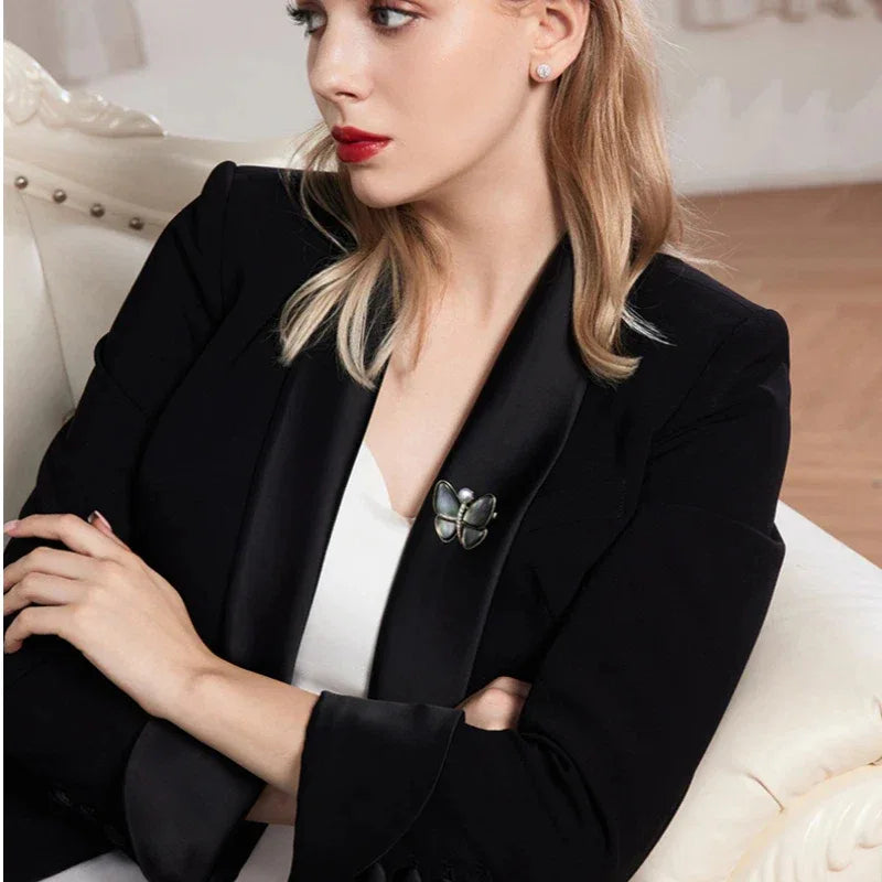 Iridescent Shell Butterfly Brooch with Shell Pearl — seated model wearing the brooch on a dark blazer