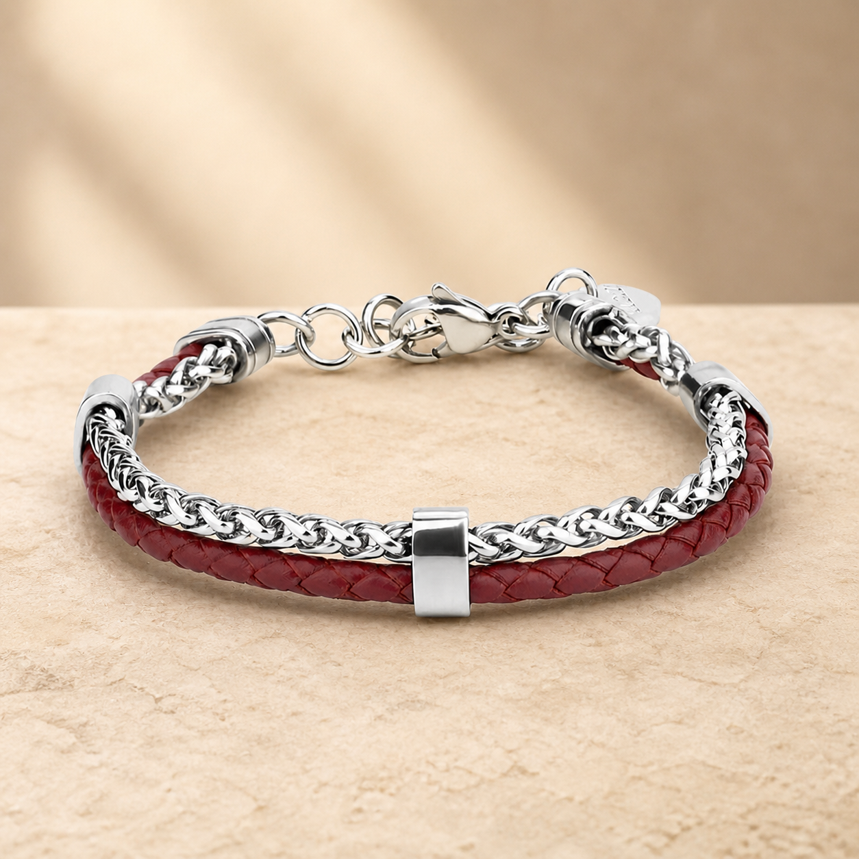 Burgundy leather and silver-tone double-layer bracelet on a warm beige stone surface