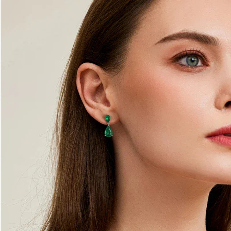 Double Pear-Cut Emerald Drop Earrings worn on the ear in a close-up