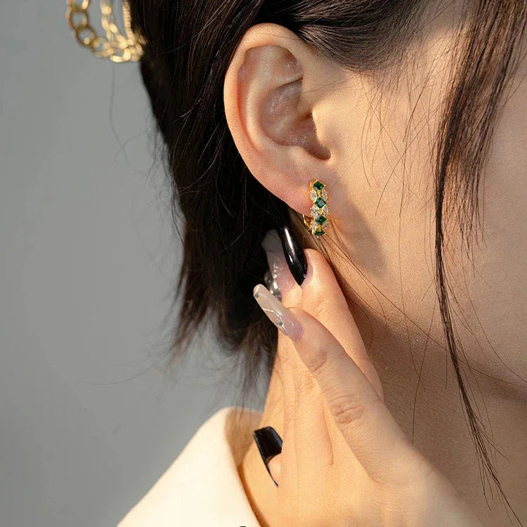 Emerald and Marquise Huggie Hoop Earrings worn on the ear in a close-up