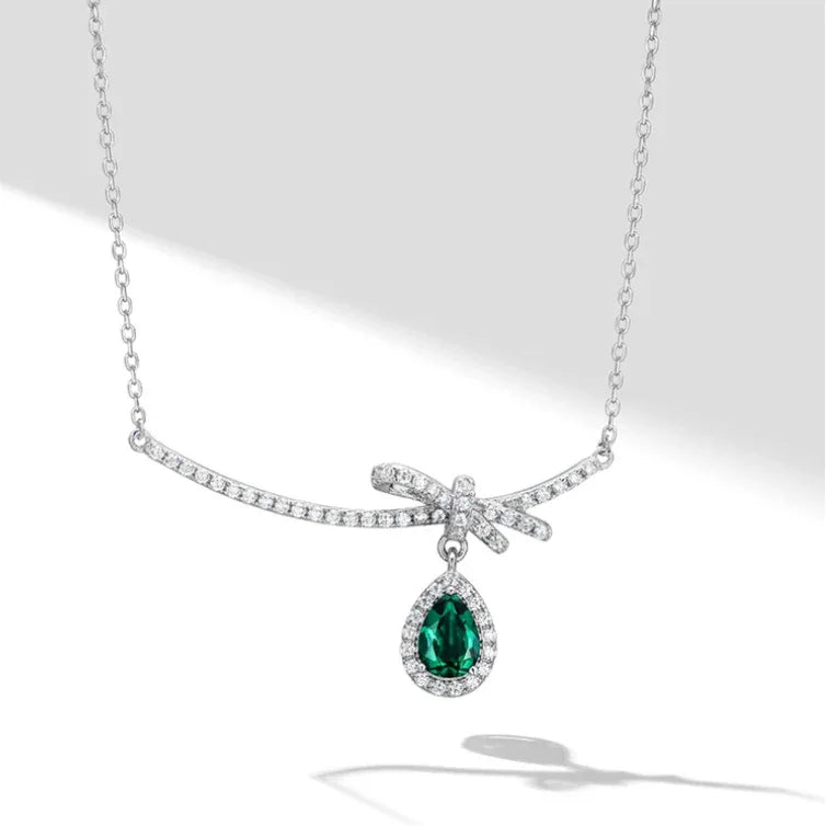 Emerald Bow and Pear Drop Necklace pendant view on a dark background