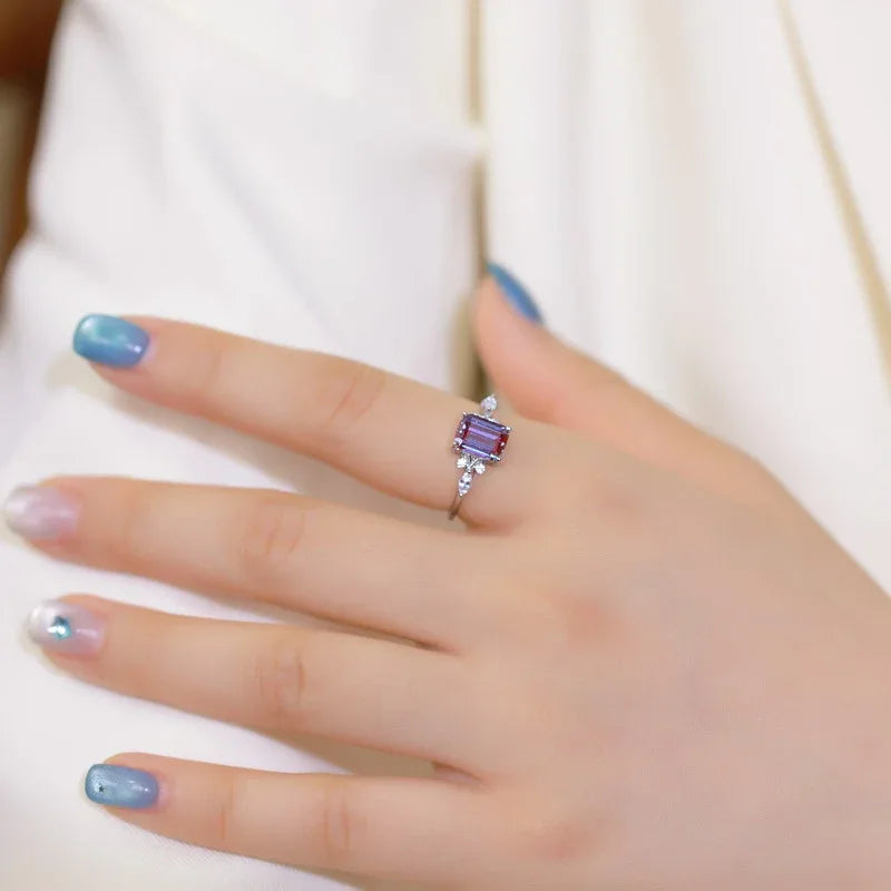Emerald-cut Alexandrite ring with leaf side accents, shown worn in a close lifestyle view