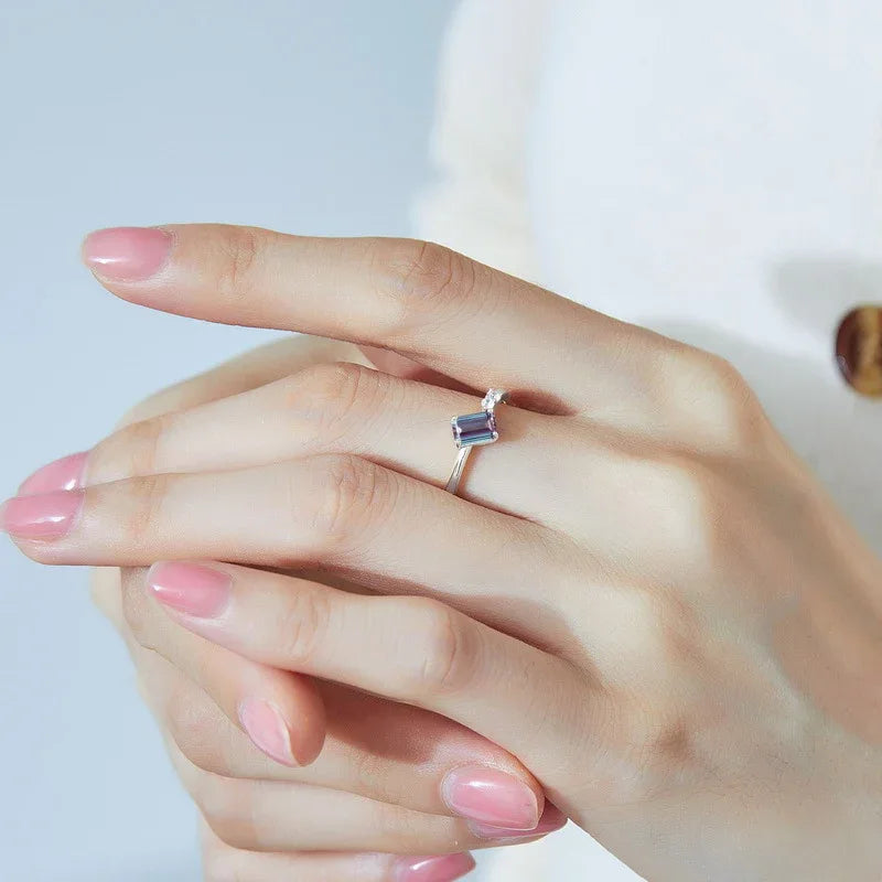 Emerald-cut Alexandrite open band ring with round clear accents, shown worn in a close lifestyle view