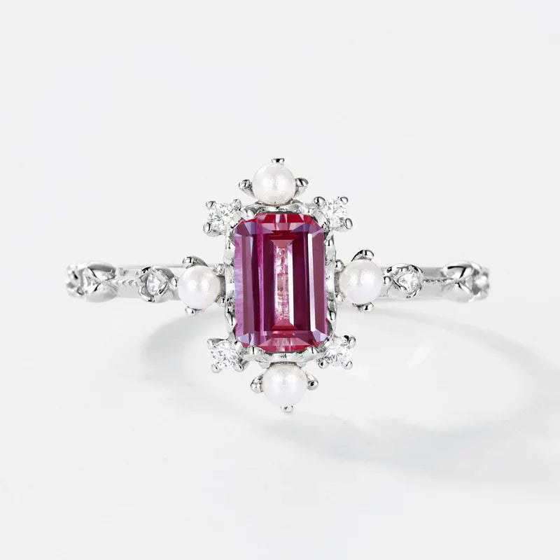 Emerald-cut Alexandrite ring with pearl and clear accents, pink-toned Alexandrite view under alternate lighting