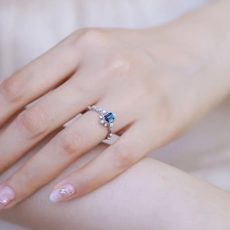 Emerald-cut Alexandrite ring with pearl and clear accents, shown worn in a close lifestyle view