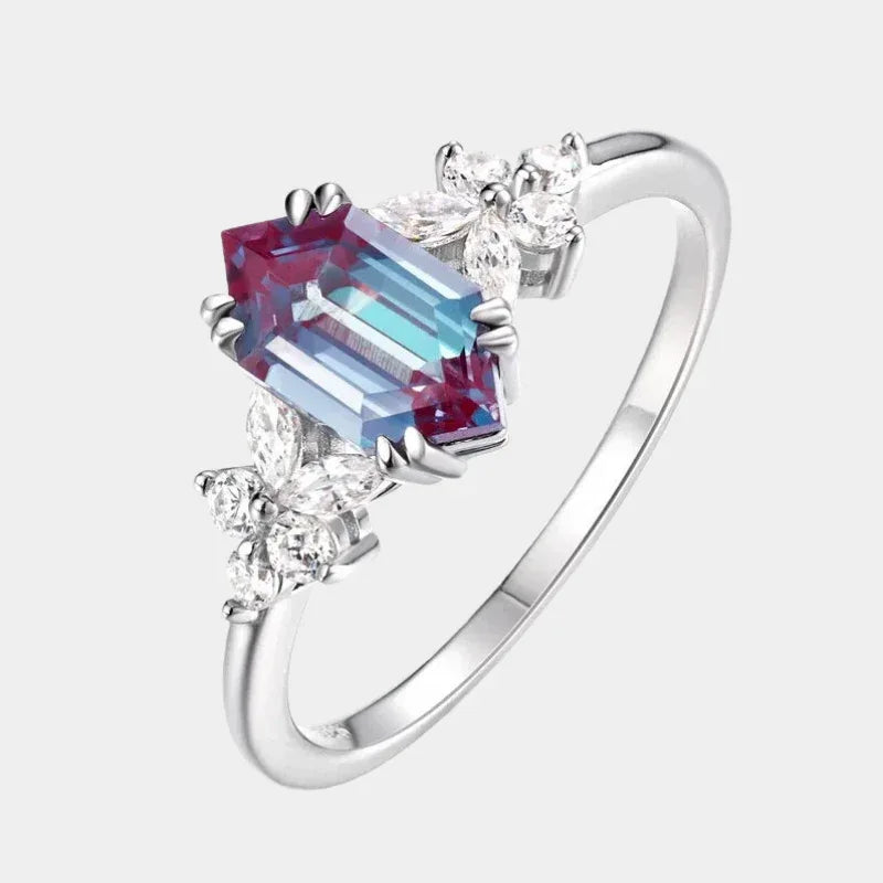 Emerald-cut Alexandrite ring with clear-stone side clusters, front product view on a white background