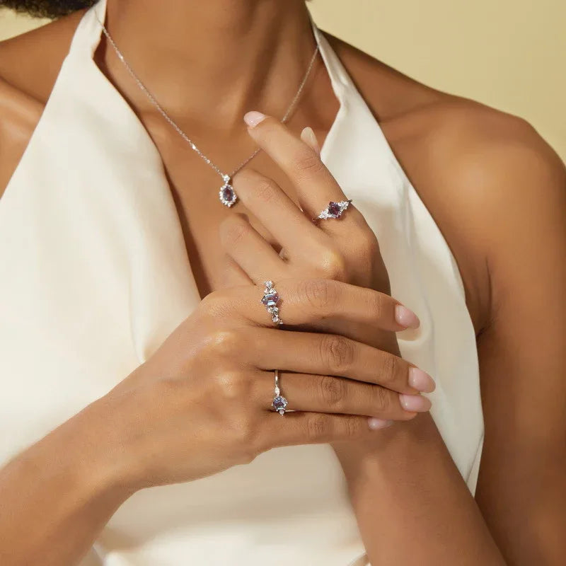 Emerald-cut Alexandrite ring with clear-stone side clusters, shown worn by a model for scale