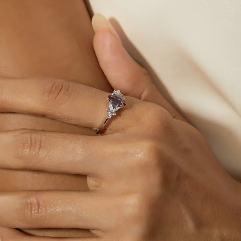 Emerald-cut Alexandrite ring with clear-stone side clusters, shown worn in a close lifestyle view