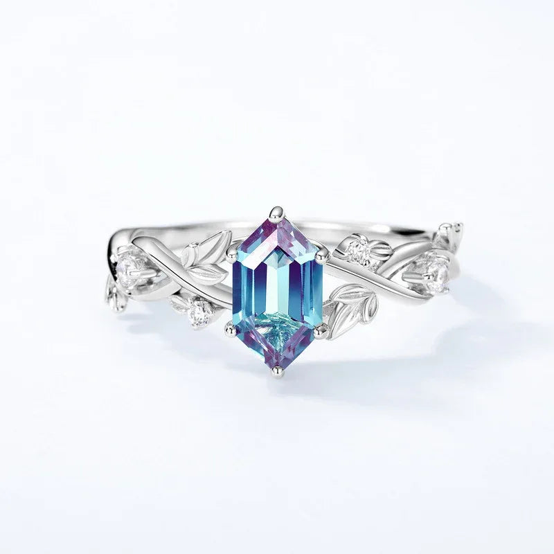 Emerald-cut Alexandrite ring with a vine and leaf band, center stone close-up on a white background