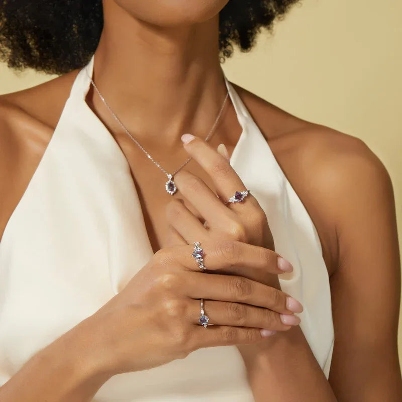 Emerald-cut Alexandrite ring with a vine and leaf band, shown worn by a model for scale