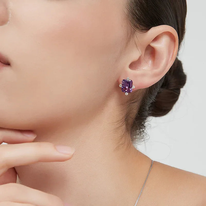 emerald-cut amethyst stud earrings worn on the ear in a close-up