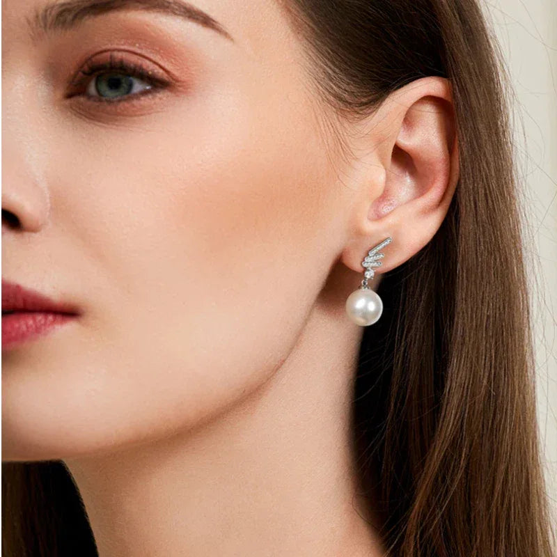 Pearl Wing Drop Earrings — right-ear worn portrait showing the drop length