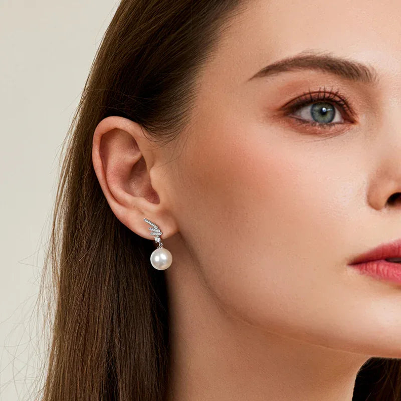 Pearl Wing Drop Earrings — left-ear worn portrait from a slightly wider angle