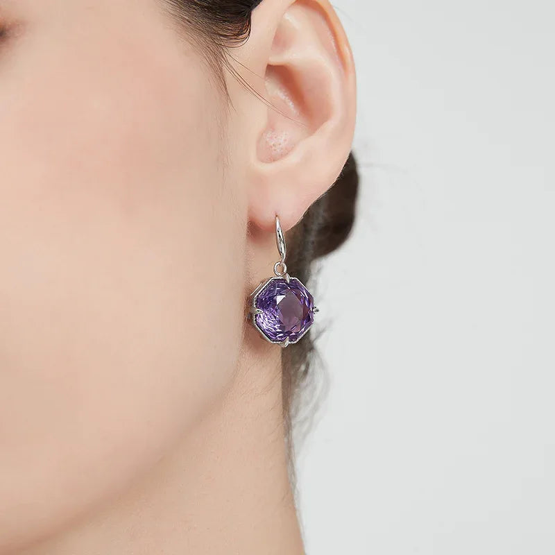 fancy-cut amethyst hook earrings worn on the ear in a close-up