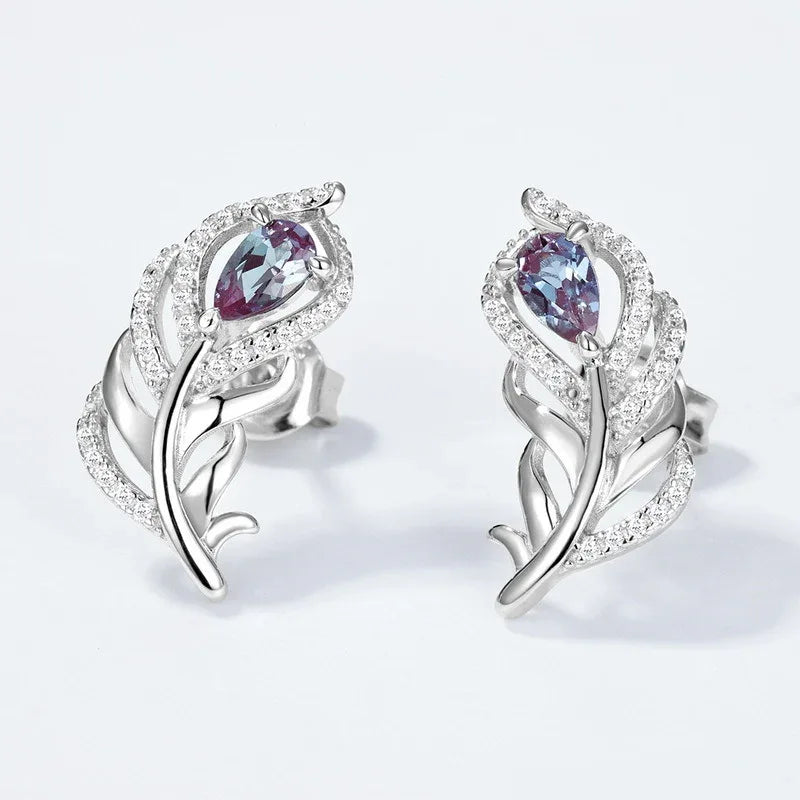 Feather-shaped stud earrings with oval Alexandrites, center stone close-up on a white background