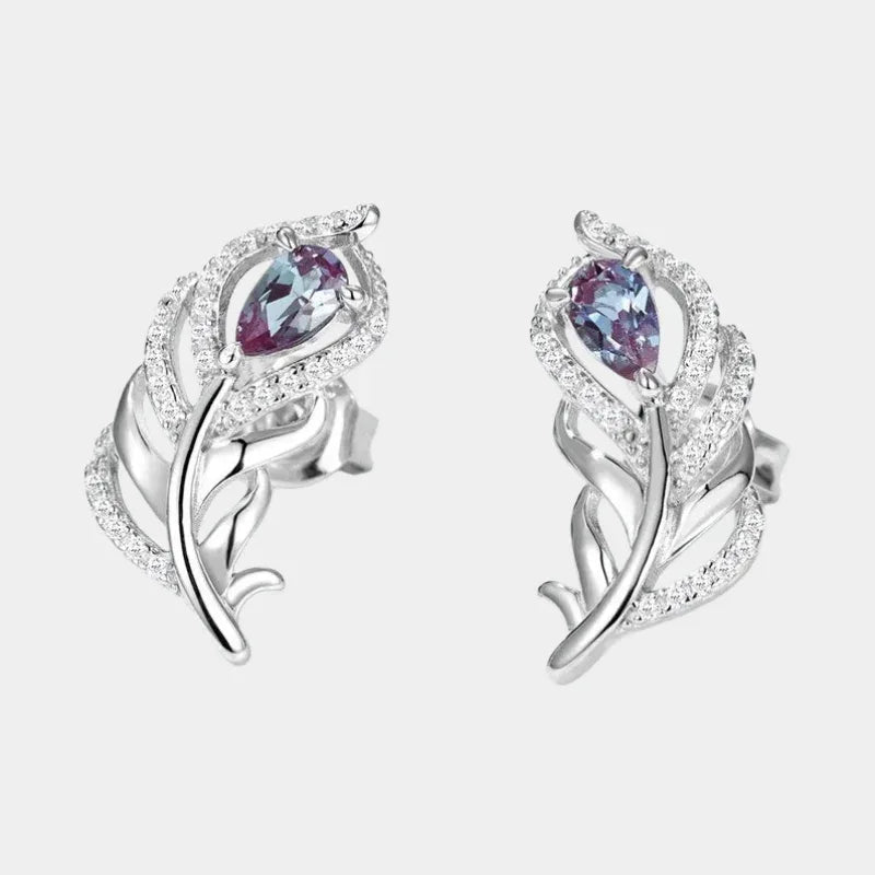 Feather-shaped stud earrings with oval Alexandrites, front product view on a white background