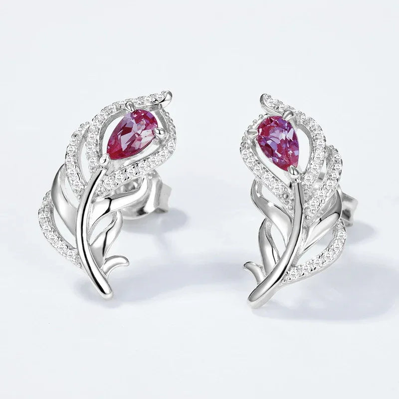Feather-shaped stud earrings with oval Alexandrites, pink-toned Alexandrite view under alternate lighting