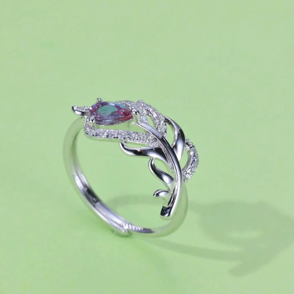 Feather-wrap ring with a Alexandrite and clear accents, angled product view on a colored background