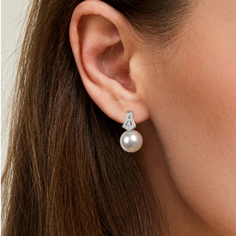 Pearl Drop Earrings with Geometric Fan Detail — close right-ear worn view showing scale