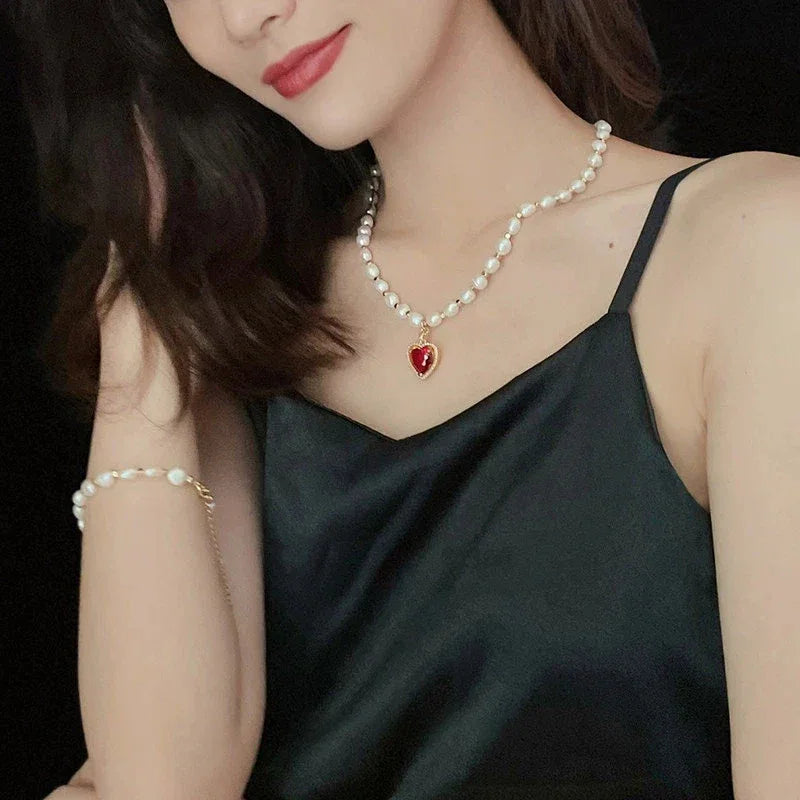 Pearl Strand Necklace with Red Heart Pendant — portrait wearing the necklace above a black camisole