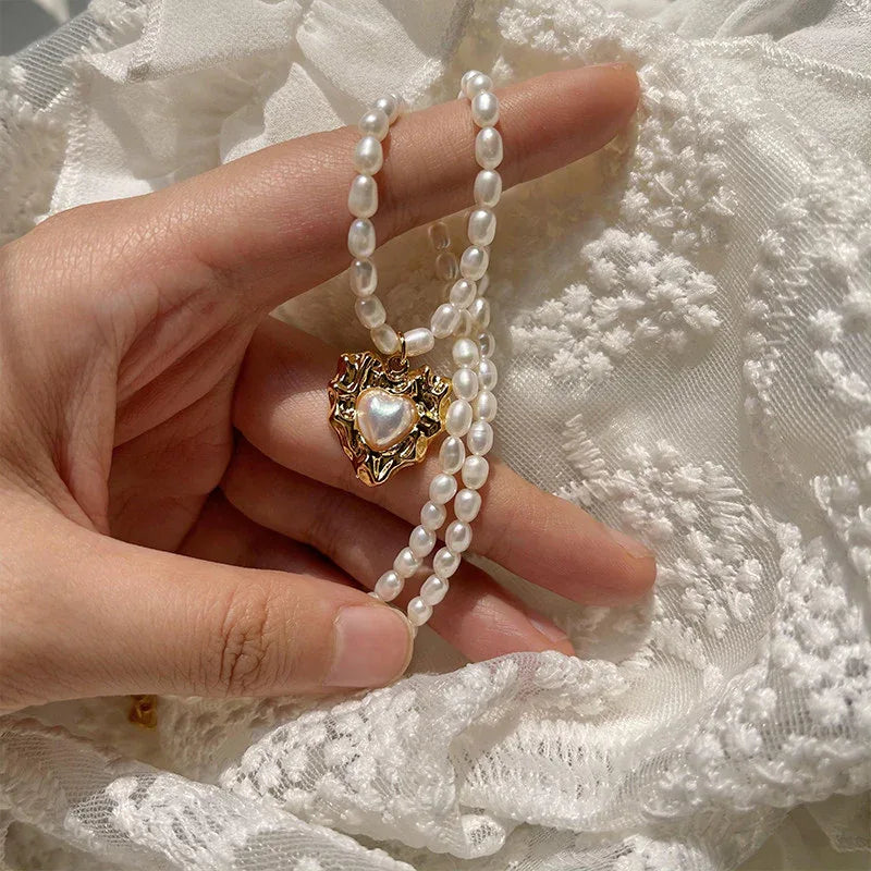 Pearl Heart Pendant Necklace with Gold-Tone Frame — hand-held close-up of the heart pendant beside pearls