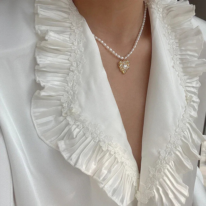 Pearl Heart Pendant Necklace with Gold-Tone Frame — neckline-worn view over a white ruffled blouse