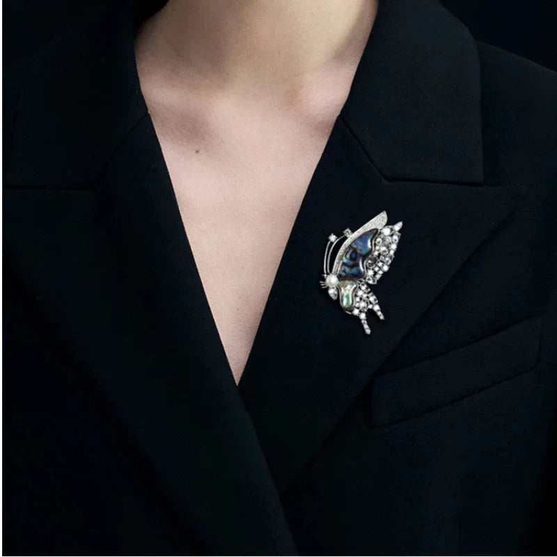 Blue-Green Mother-of-Pearl Butterfly Brooch with Pearl — close black-blazer worn view showing scale