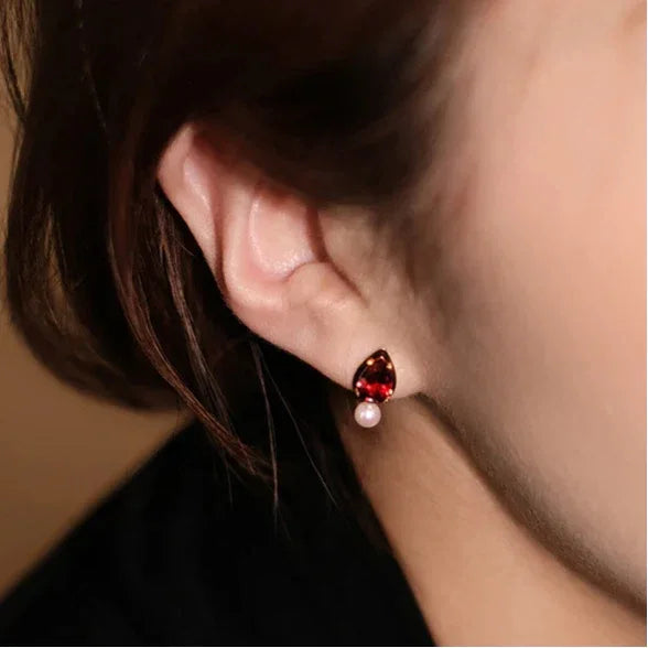 Garnet and Pearl Teardrop Earrings worn on the hand in a close-up