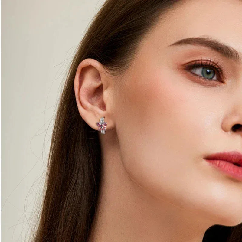 Garnet Butterfly Huggie Hoop Earrings worn on the hand in a close-up