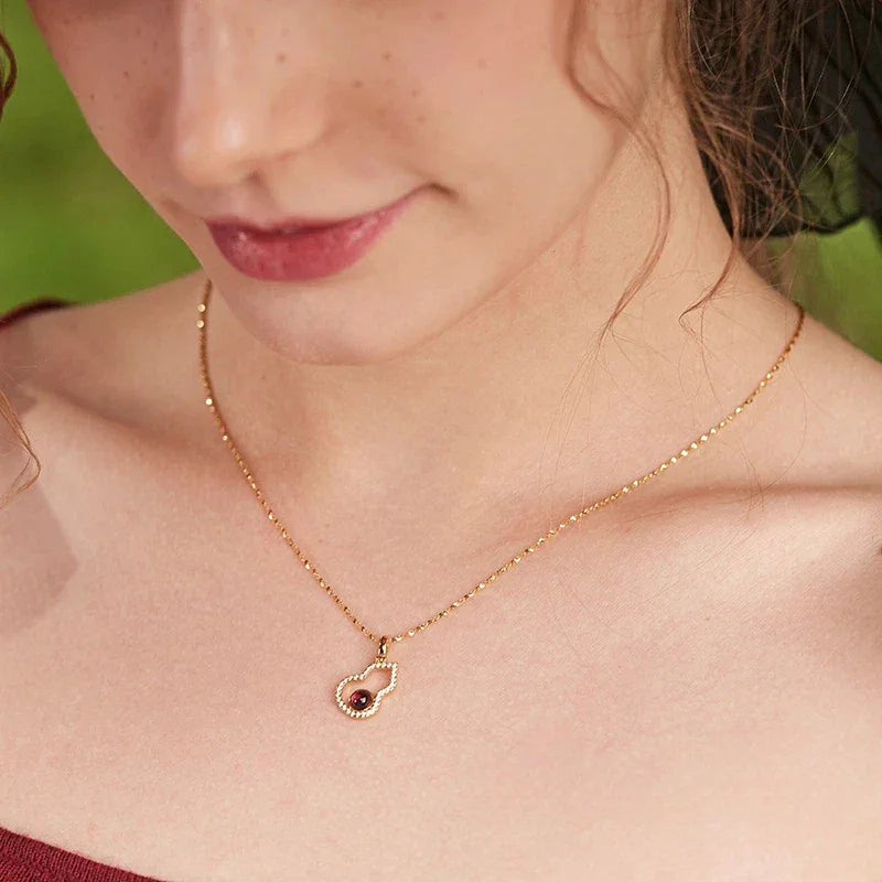 Garnet Gourd Halo Pendant Necklace worn at the neckline in a close-up