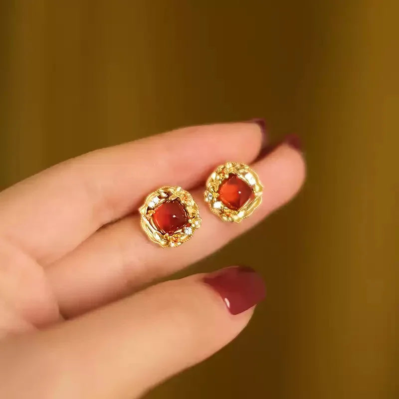 Garnet Rope-Halo Stud Earrings worn on the hand in a close-up