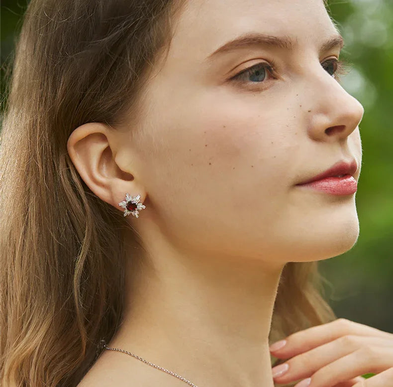 Garnet Snowflake Halo Stud Earrings side view held between the fingers