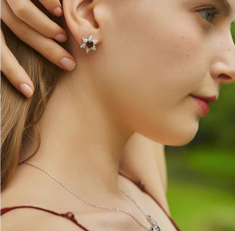 Garnet Snowflake Halo Stud Earrings worn on the hand in a close-up